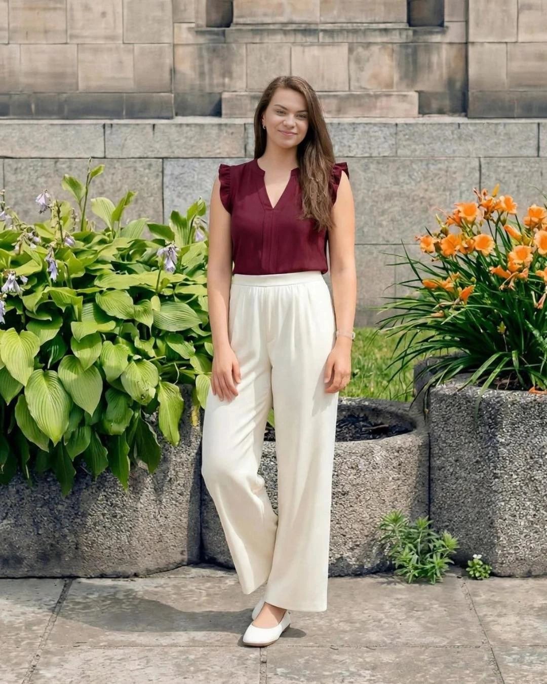 A burgundy sleeveless top with cream wide-leg trousers and white ballet flats