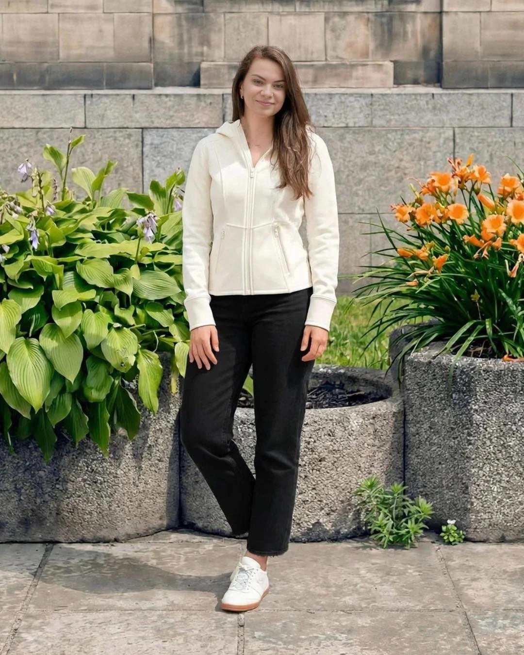 Eine cremefarbene Zip-Jacke mit schwarzer Jeans mit geradem Bein und weißen Sneakern