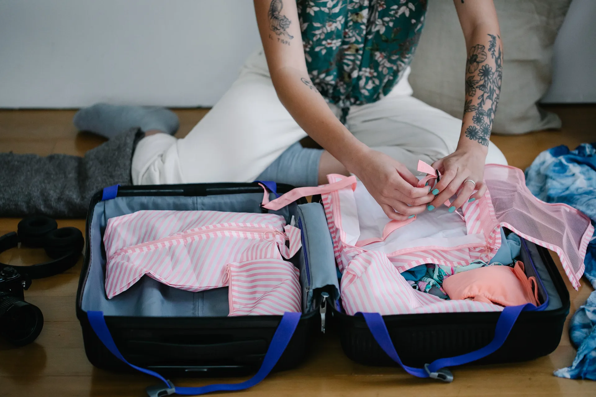 Hands folding clothes into an open suitcase while packing for a trip