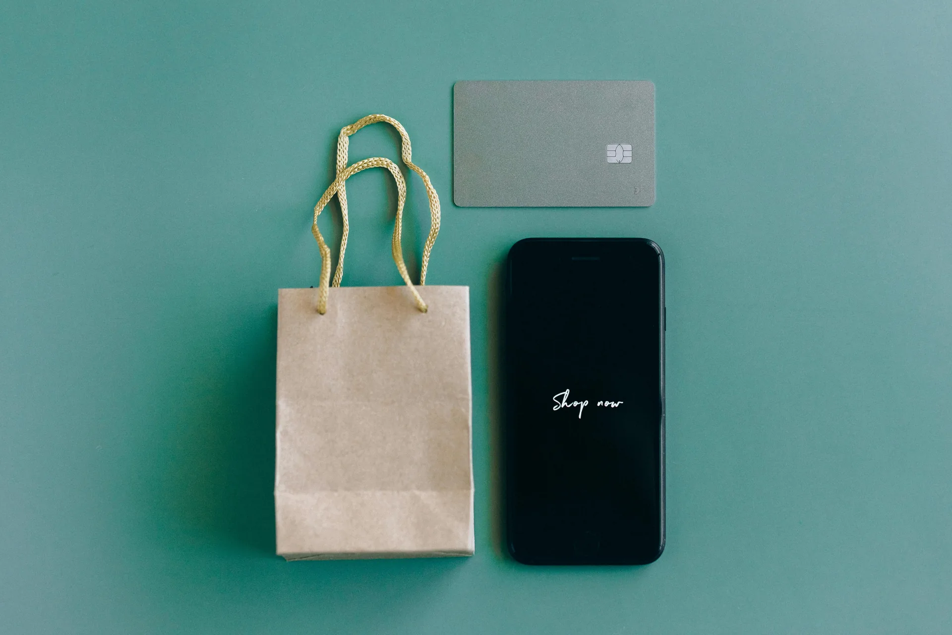 A shopping bag, payment card, and phone laid out flat on a table
