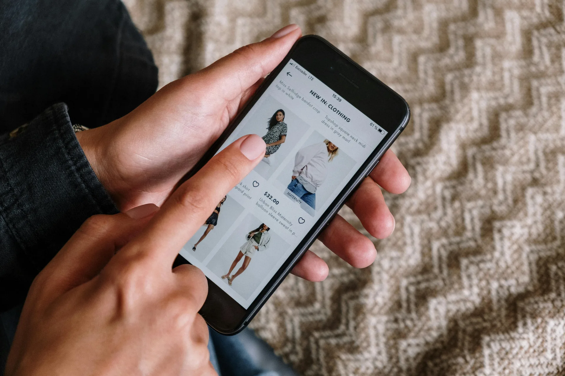 Hands holding a phone open to a clothing shopping app